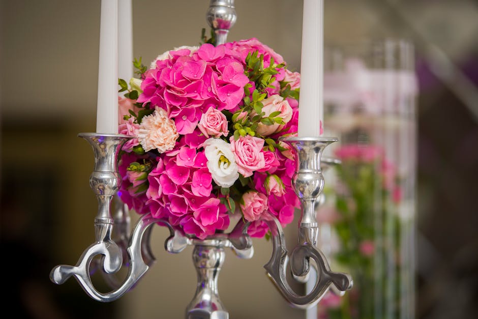 A floral arrangement featuring a bouquet of vibrant pink hydrangeas, soft pink roses, and white lisianthus, accented with green foliage, arranged in a round bouquet style. The flowers are displayed in